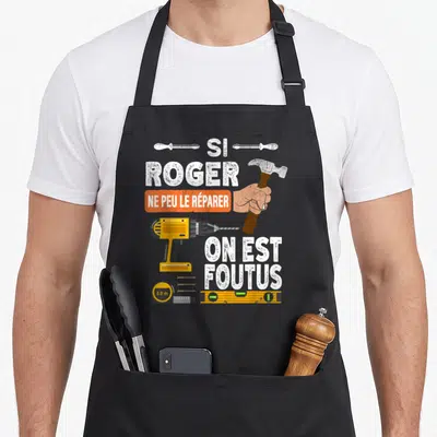 Tablier de cuisine noir avec illustration d'un marteau, perceuse jaune et texte humoristique sur fond uni.