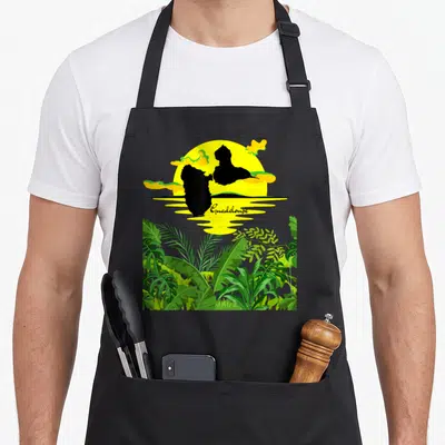 Tablier de cuisine noir avec silhouette de Guadeloupe, soleil jaune et feuilles tropicales vertes en bas.