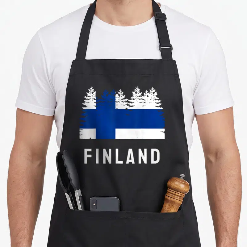 Tablier de cuisine noir avec drapeau forêt finlandaise et inscription Finland en lettres blanches capitales.