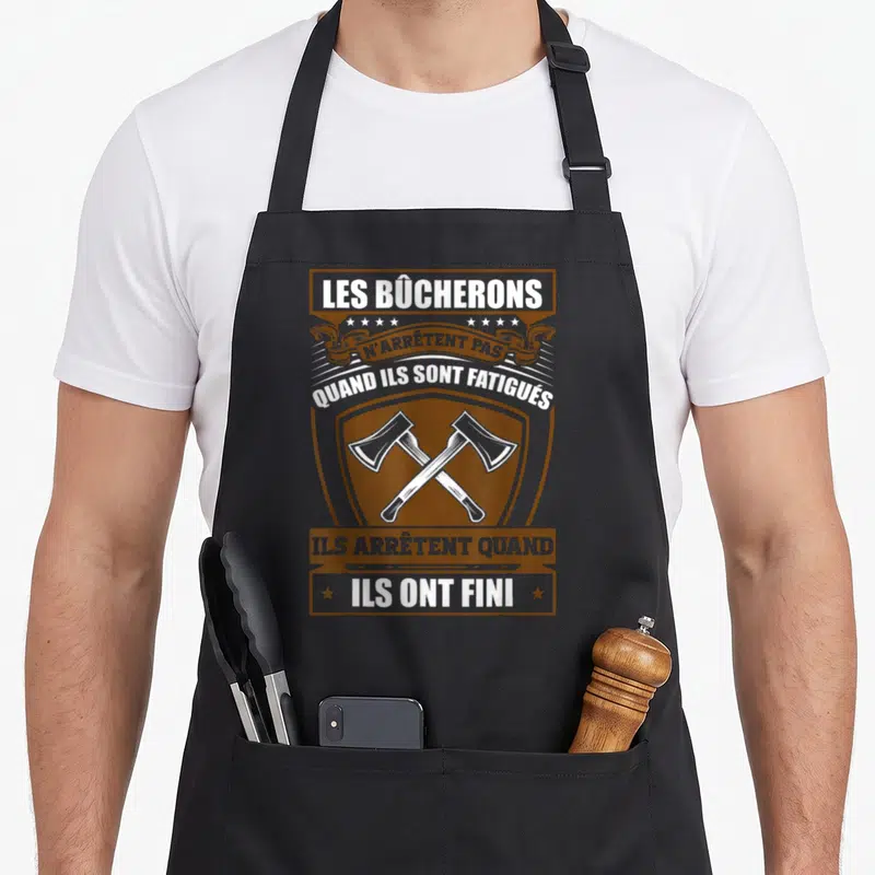 Tablier de cuisine noir avec motif Les Bûcherons et deux haches croisées en style blason.