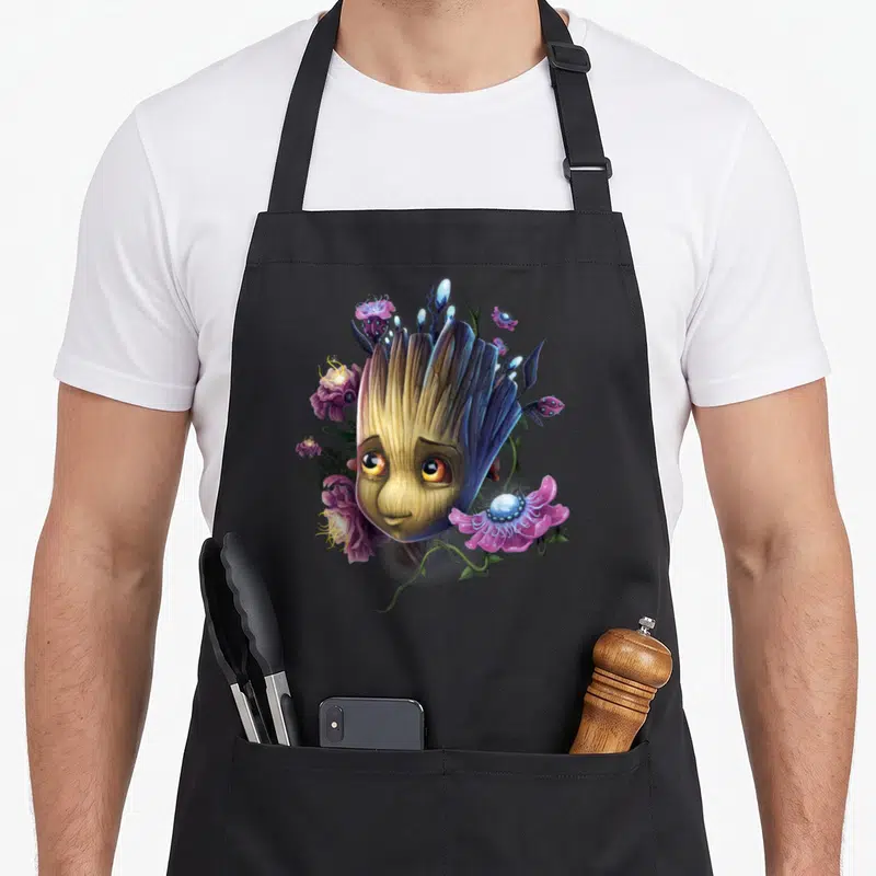 Tablier de cuisine noir avec illustration de Groot Flowers entouré de fleurs roses et de plantes fantaisistes.