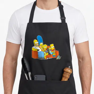 Tablier de cuisine noir avec les Simpson assis sur un canapé orange, Homer tenant une télécommande.