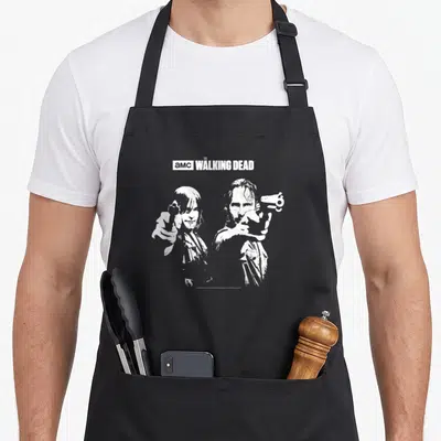 Tablier de cuisine noir avec illustration blanche de deux personnages armés du logo AMC The Walking Dead Saints