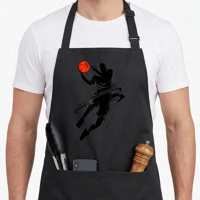 Tablier de cuisine noir avec silhouette stylisée d'un joueur de basket en train de réaliser un slam dunk avec une balle orange vif.