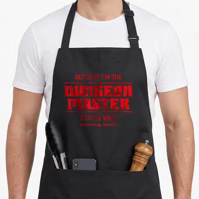 Tablier de cuisine noir avec inscription rouge Because I'm The Dungeon Master That's Why et logo Dungeons Dragons en bas.