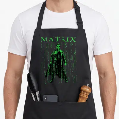 Tablier de cuisine noir avec une illustration verte de Neo et le mot Matrix en lettres digitales.