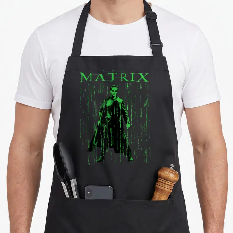 Tablier de cuisine noir avec une illustration verte de Neo et le mot Matrix en lettres digitales.