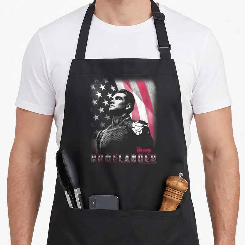 Tablier de cuisine noir avec portrait d'Homelander, drapeau américain en arrière-plan et texte rouge The Boys HOMELANDER.