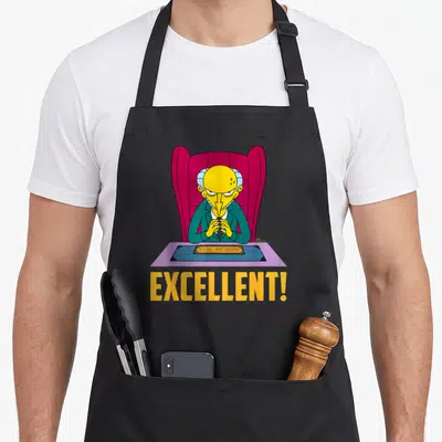 Tablier de cuisine noir avec Mr. Burns assis à son bureau et le mot Excellent en lettres jaunes.