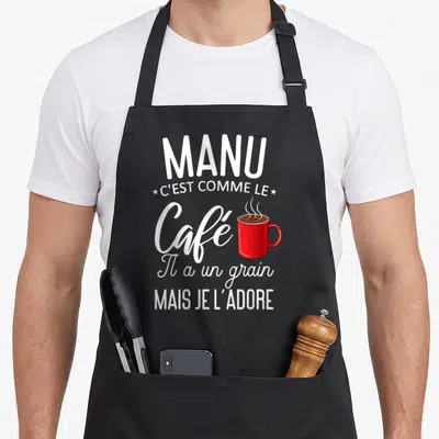 Tablier de cuisine noir avec une illustration de tasse rouge et texte blanc sur fond uni.