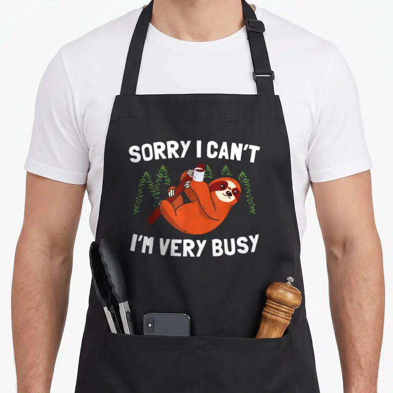 Tablier de cuisine noir avec un fourrure orange tenant une tasse et le texte Sorry I can't I'm very busy en blanc.