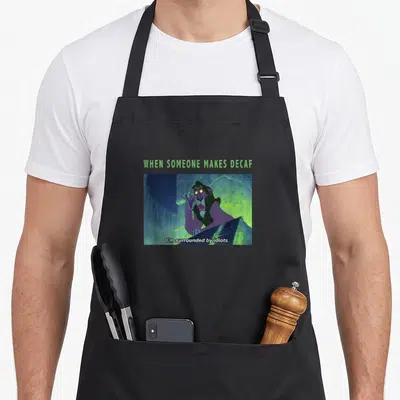Tablier de cuisine noir avec Scar et le texte When Someone Makes Decaf I'm Surrounded by Idiots imprimé en centre.