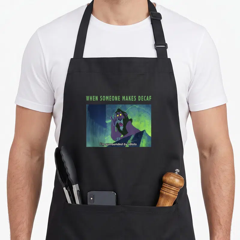 Tablier de cuisine noir avec Scar et le texte When Someone Makes Decaf I'm Surrounded by Idiots imprimé en centre.