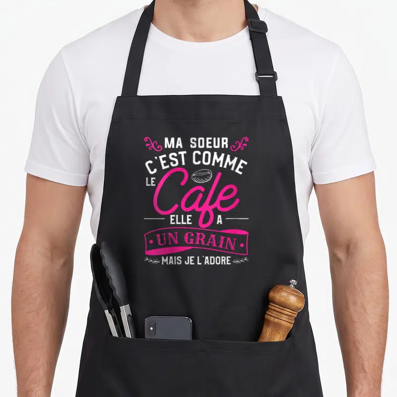 Tablier de cuisine noir avec inscription rose et blanche Ma Soeur C'est Comme Le Cafe Un Grain Mais Je L'Adore et une graine de café.