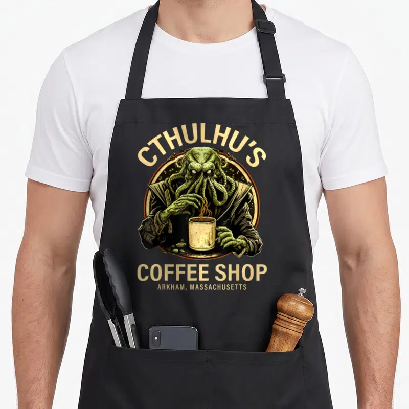 Tablier de cuisine noir avec une illustration verte de Cthulhu tenant une tasse de café chaud.