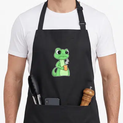 Tablier de cuisine noir avec illustration d'un lézard vert grincheux tenant une tasse orange fumante.