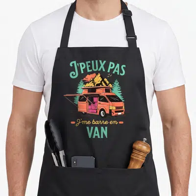 Tablier de cuisine noir avec illustration d'un van orange sur fond de montagnes et texte J'peux pas j'me barre en van.