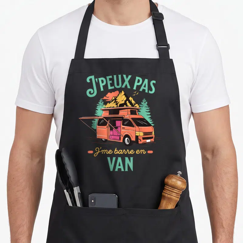 Tablier de cuisine noir avec illustration d'un van orange sur fond de montagnes et texte J'peux pas j'me barre en van.