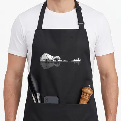 Tablier de cuisine noir avec illustration blanche de forêts et skyline urbain reflétés dans l'eau.