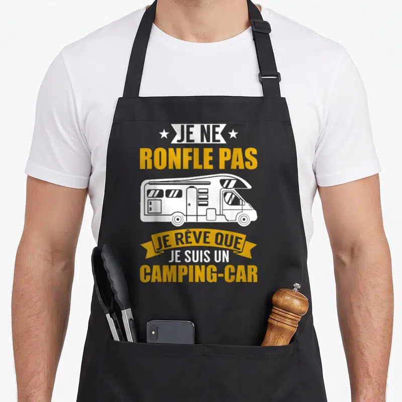 Tablier de cuisine noir avec une illustration blanche d'un camping-car et le texte jaune Je ne ronfle pas je rêve que je suis un camping-car.
