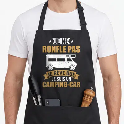 Tablier de cuisine noir avec inscription humoristique sur le camping et illustration d'un camping-car blanc stylisé.
