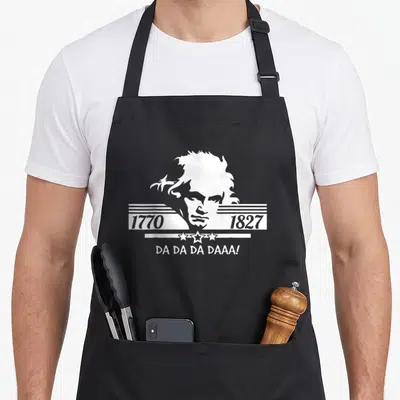 Tablier de cuisine noir avec portrait stylisé de Ludwig Van Beethoven Compositeur Pianiste et les dates 1770 1827 Da Da Da Daaa en blanc.