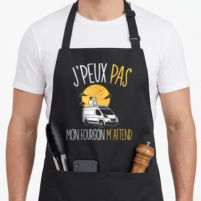 Tablier de cuisine noir avec illustration de van blanc, couple sur le toit et texte J'peux pas mon fourgon m'attend.