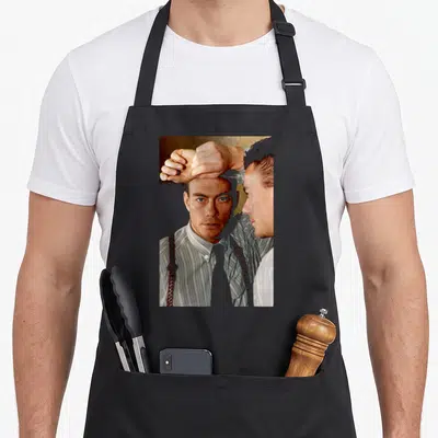 Tablier de cuisine noir avec une illustration de Jean-Claude Van Damme en chemise à bretelles et poing levé.
