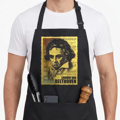 Tablier de cuisine noir avec portrait stylisé de Ludwig van Beethoven sur fond de partitions musicales jaunes et grises.