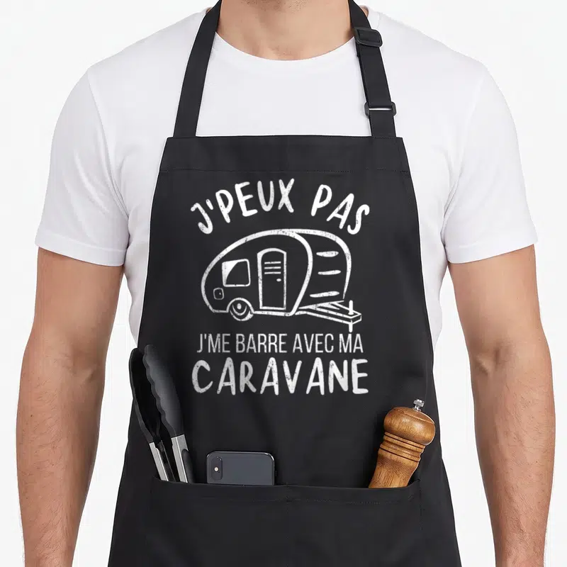 Tablier de cuisine noir avec illustration blanche d'une caravane et texte humoristique sur le camping.