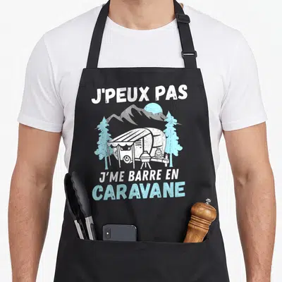 Tablier de cuisine noir avec illustration d'une caravane blanche, de pins bleus et du texte J'peux pas j'me barre en caravane