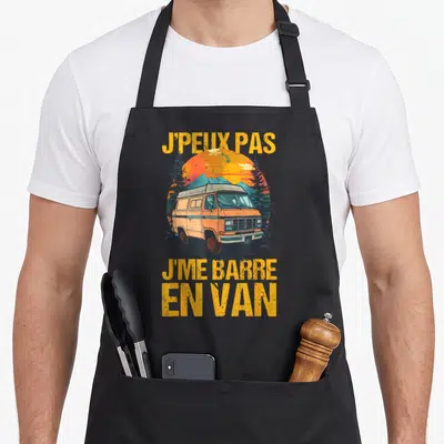 Tablier de cuisine noir avec illustration de van orange et texte jaune sur fond de montagne.