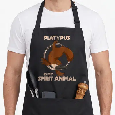 Tablier de cuisine noir avec illustration dornithorynque et texte platypus is my spirit animal en beige vintage.