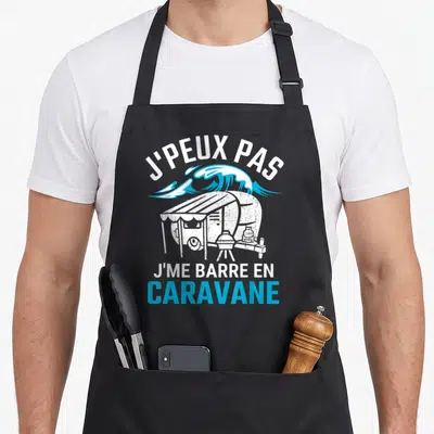Tablier de cuisine noir avec illustration blanche et bleue d'une caravane sous une vague et le texte J'peux pas j'me barre en caravane.