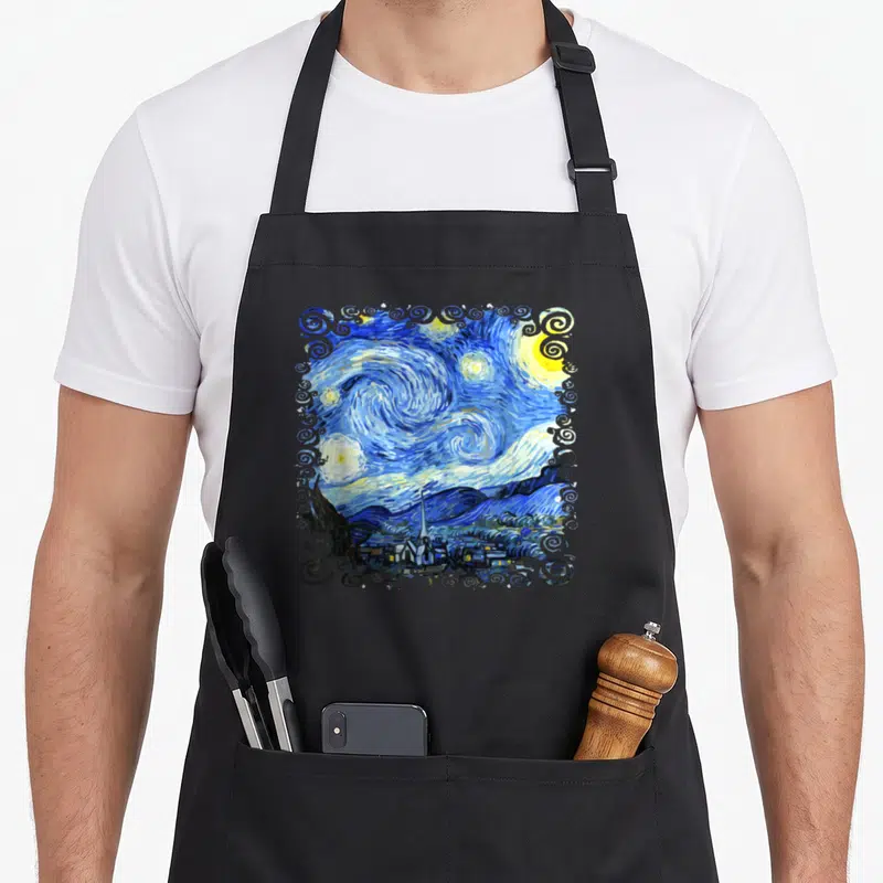 Tablier de cuisine noir avec reproduction de La Nuit étoilée encadrée de motifs tourbillonnants bleus et blancs.