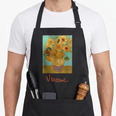 Tablier de cuisine noir avec une impression du tableau Vase aux 12 Tournesols et la signature Vincent en orange.