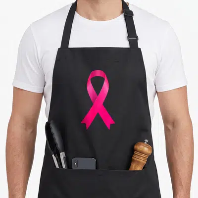 Tablier de cuisine noir avec un grand ruban rose brillant au centre pour la sensibilisation.