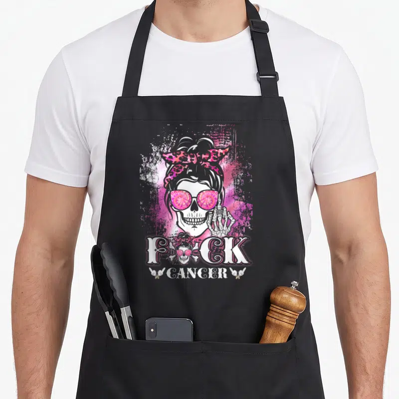 Tablier de cuisine noir avec un crâne de femme aux lunettes roses et l'inscription F*ck Cancer en blanc.