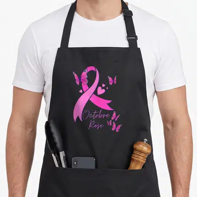 Tablier de cuisine noir avec ruban rose, papillons et texte Octobre Rose imprimé en violet.