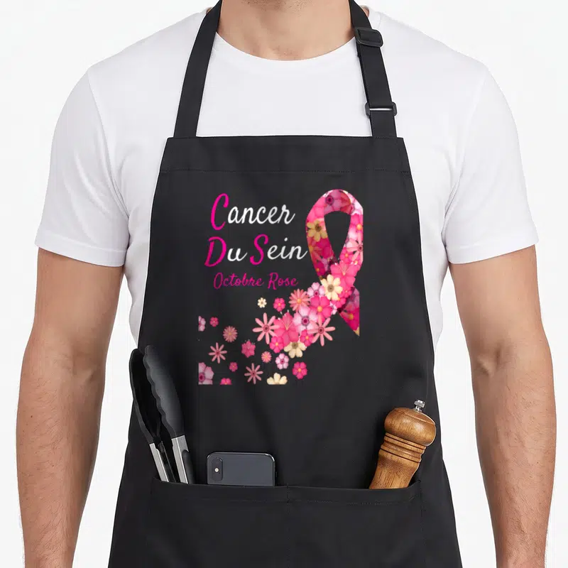 Tablier de cuisine noir avec un ruban rose composé de fleurs et le texte Cancer Du Sein Octobre Rose imprimé en rose et blanc.