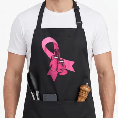 Tablier de cuisine noir avec un grand ruban rose sur lequel pendent deux gants de boxe roses dessinés au trait.