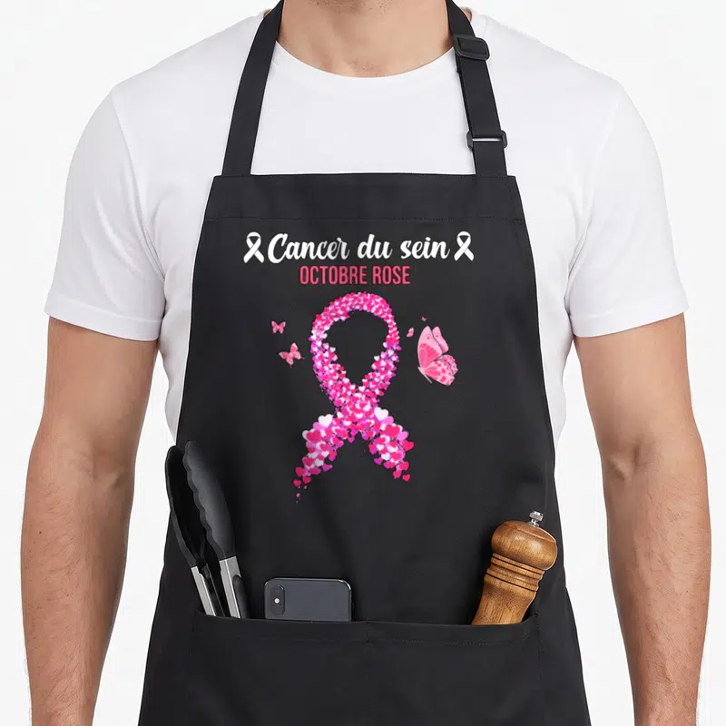 Tablier de cuisine noir avec un ruban rose fait de cœurs, des papillons et le texte Cancer du sein Octobre Rose.