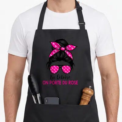 Tablier de cuisine noir avec illustration femme chignon rubans roses lunettes et texte En Octobre on porte du rose