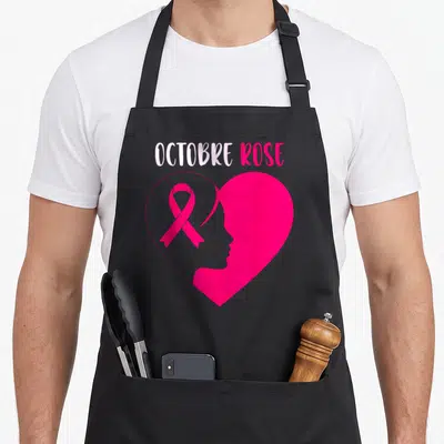 Tablier de cuisine noir avec un grand cœur rose, un ruban symbolique et le profil d'une femme en silhouette.