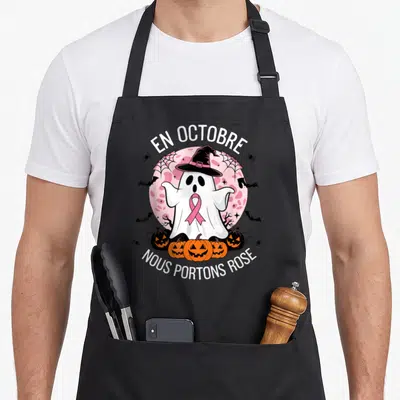 Tablier de cuisine noir avec un fantôme portant un ruban rose, des citrouilles et le texte En Octobre Nous Portons Rose.