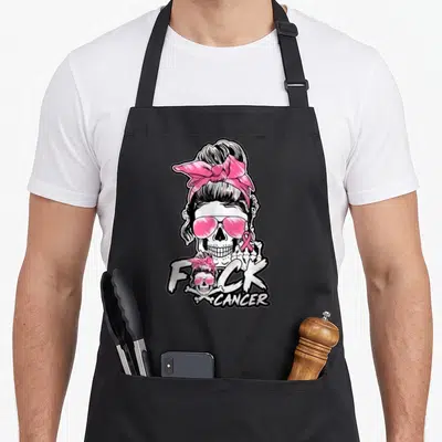 Tablier de cuisine noir avec un crâne aux lunettes roses et le message F*ck Cancer imprimé en blanc.
