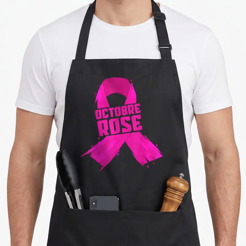 Tablier de cuisine noir orné d'un ruban rose vif aux contours épurés et du texte Octobre Rose au centre.