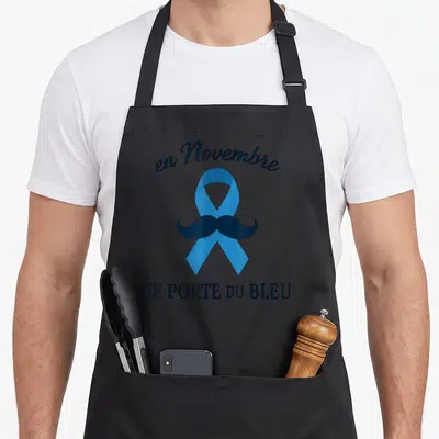 Tablier de cuisine noir avec un ruban bleu, une moustache noire et le texte en novembre je porte du bleu imprimé au centre.