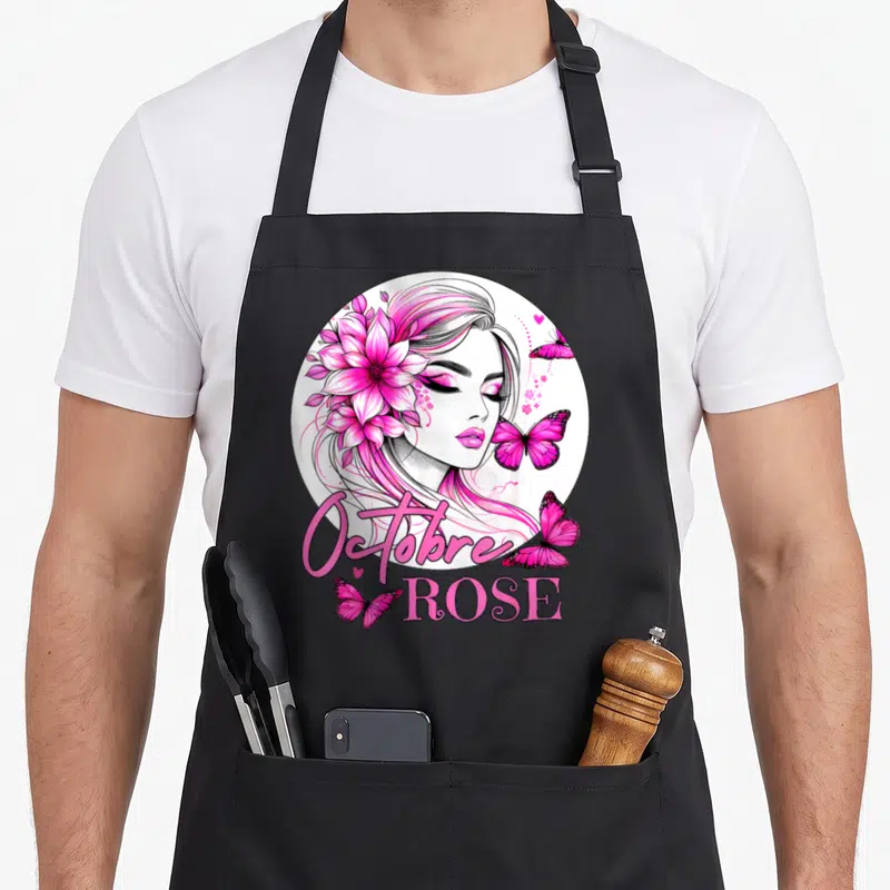 Tablier de cuisine noir avec illustration d'une femme aux cheveux roses, des papillons et le texte Octobre Rose.