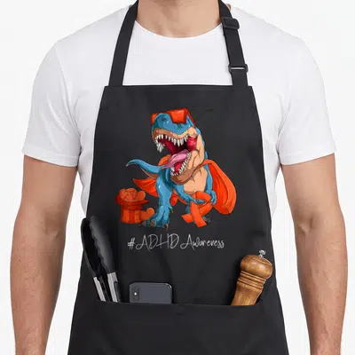 Tablier de cuisine noir avec un dinosaure magicien orange portant des lunettes et sortant un ruban d'un chapeau.